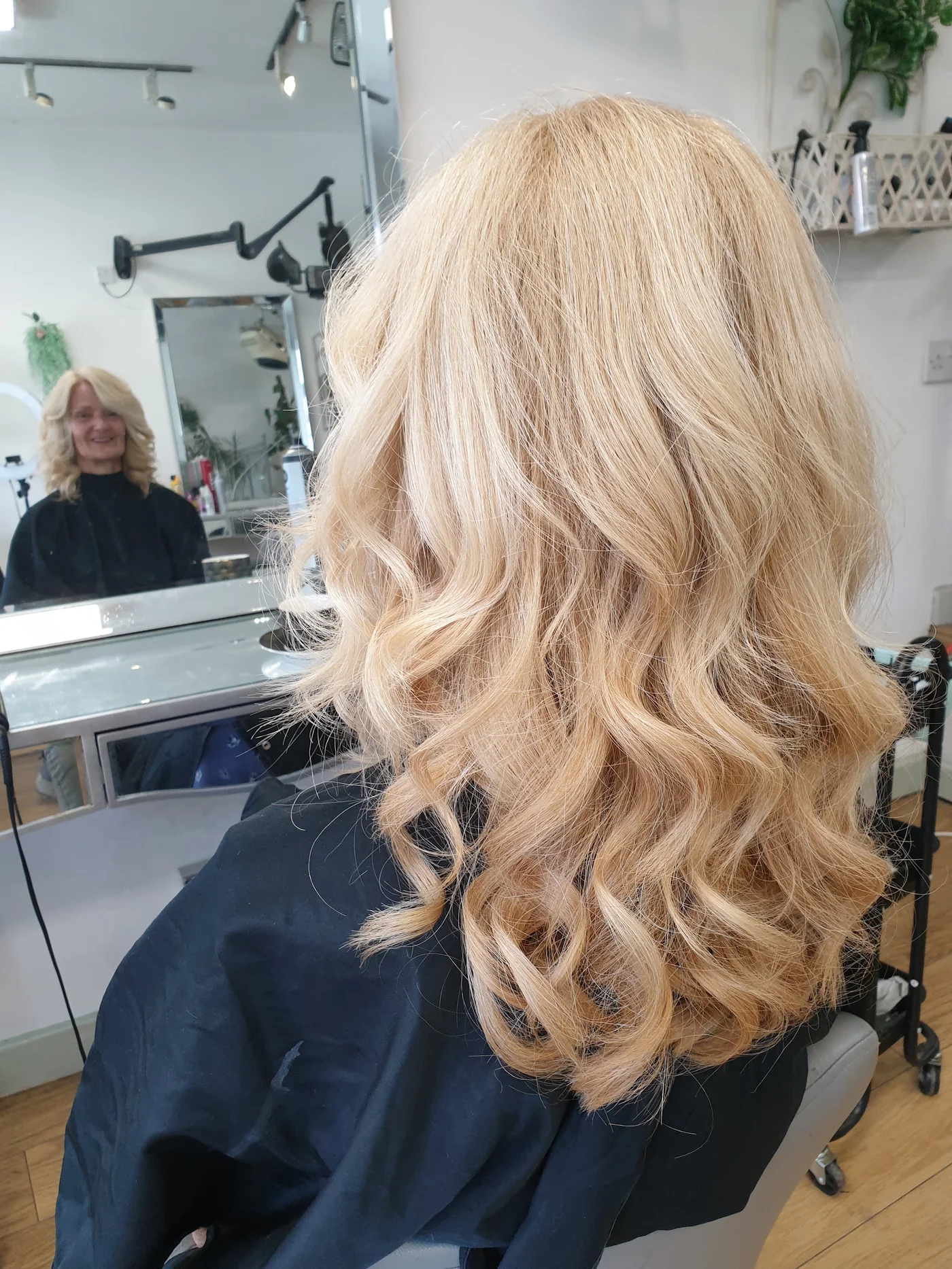 Finished curls seen from the side, reflected in the salon mirror